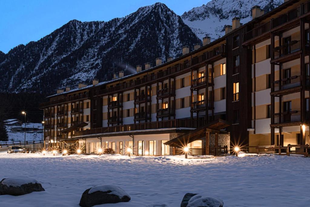 un hotel nella neve con montagne sullo sfondo di Maison Poluc hotel apartments a Champoluc