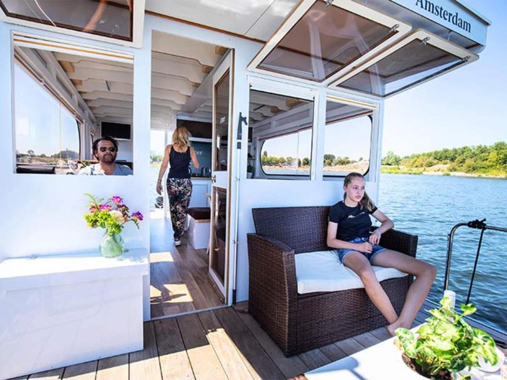 una mujer sentada en una silla en la parte trasera de un barco en Amazing houseboat in Kinrooi for rent, en Kinrooi