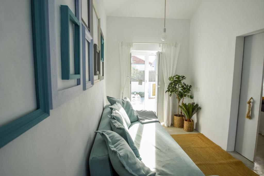 sala de estar con sofá verde y ventana en Casa do Povo (casa com piscina no centro de Alcácer), en Alcácer do Sal