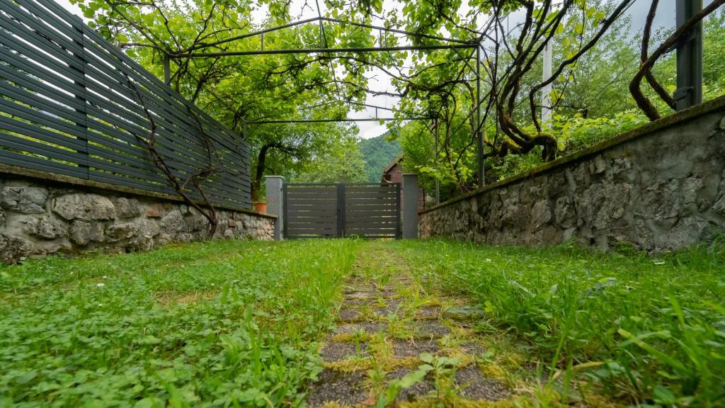 a stone wall and a fence next to a yard at Holiday house Kajfes in Brod na Kupi