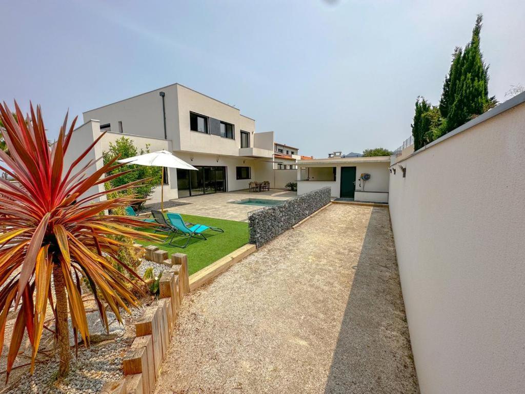 un patio trasero de una casa con jardín y una casa en L'Attrape Rêves en Villelongue-dels-Monts