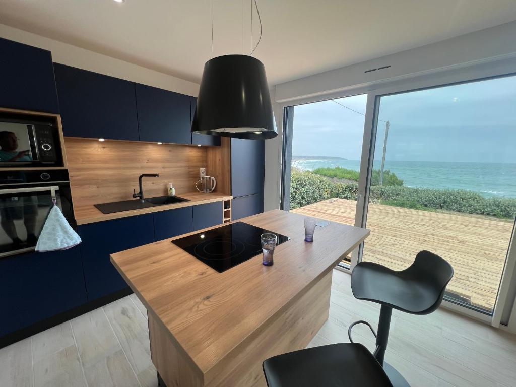 uma cozinha com uma ilha com vista para o oceano em Le bruit des vagues em Les Pieux