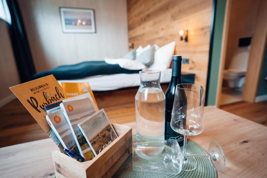 una mesa con una botella de vino y copas. en Pur-INN das Gästehaus en Purbach am Neusiedlersee