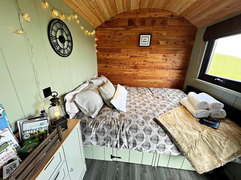 1 dormitorio con 1 cama y reloj en la pared en Luxury Shepherd Hut in the Peak District, en Bakewell