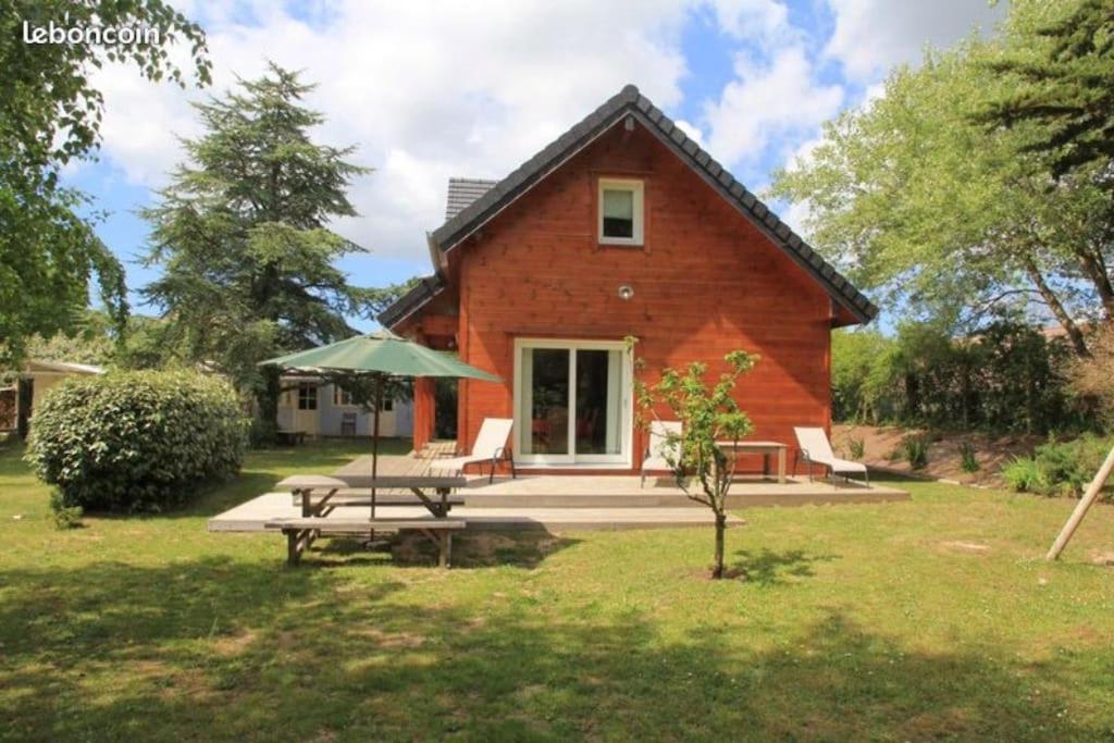 a house with a picnic table in front of it at Charmante maison en bois proche mer in Saint-Jean-de-la-Rivière