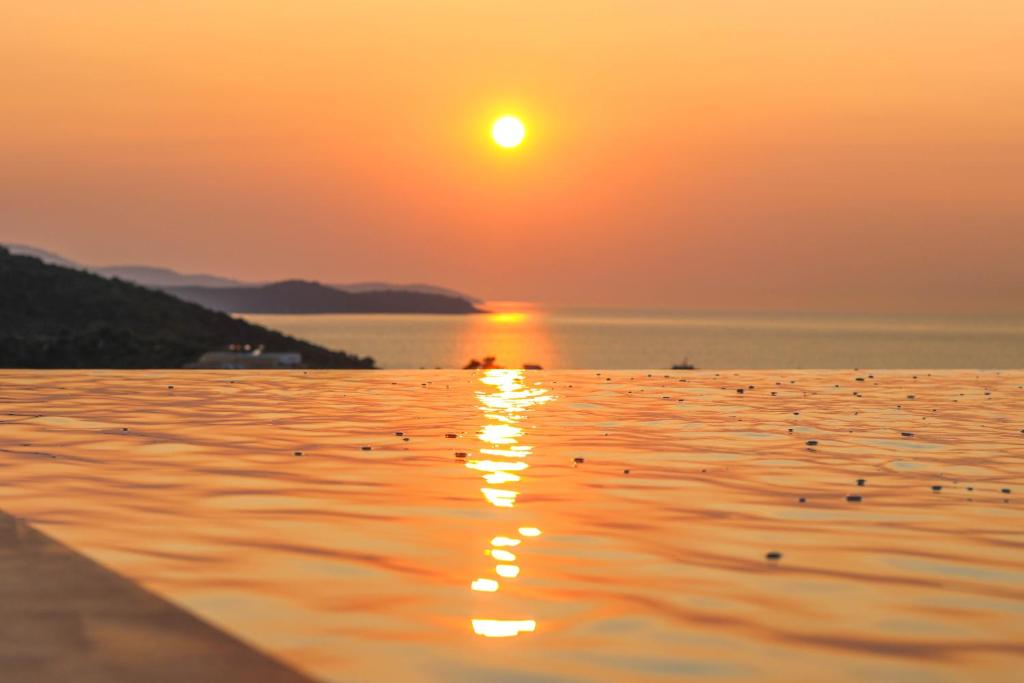 una puesta de sol sobre un cuerpo de agua con aves en el agua en Lans Hotel, en Ksamil