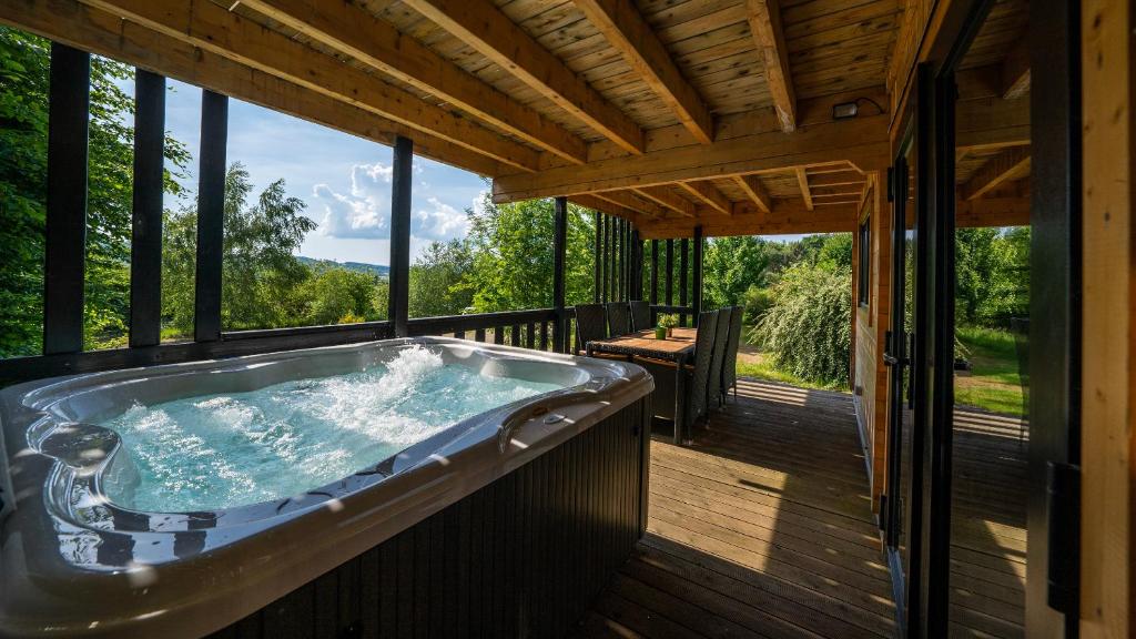 a jacuzzi tub on the deck of a cabin at Le Village des Monédières in Chamberet