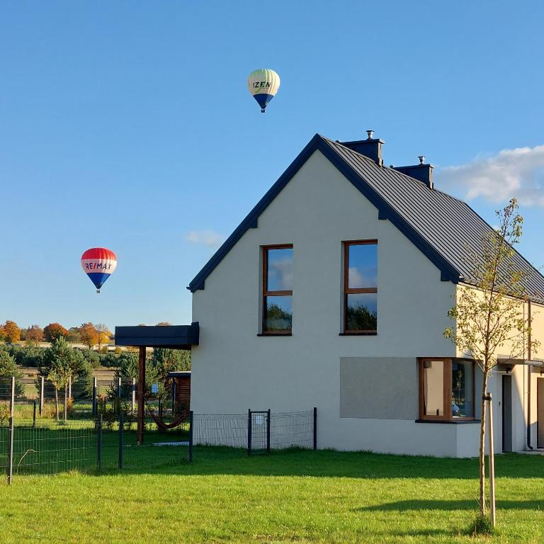 a white house with two hot air balloons in the sky at Moje Miejsce Jura in Kroczyce
