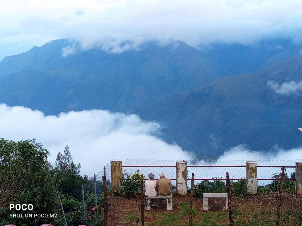 two people sitting on a bench looking at the mountains at The Views - True Baduaga Living in Ooty