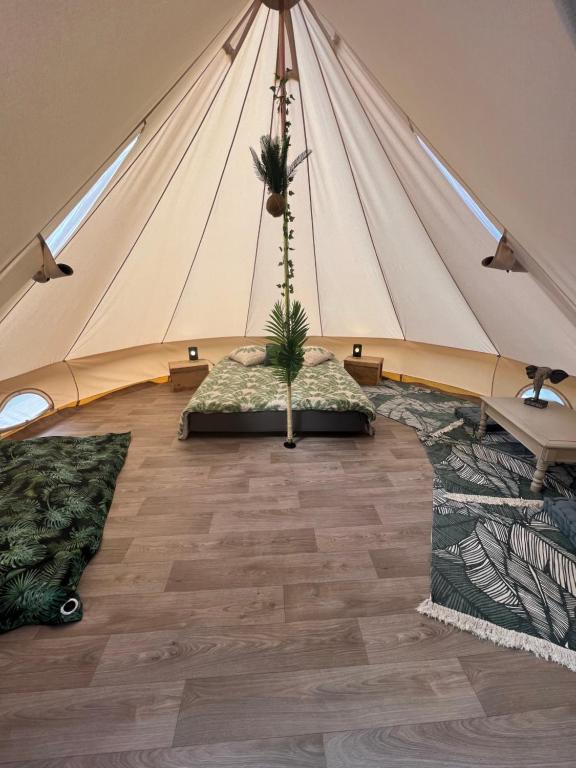 uma tenda com uma planta no meio de uma sala em Le Tipi Tropical au bord de la rivière em Mios
