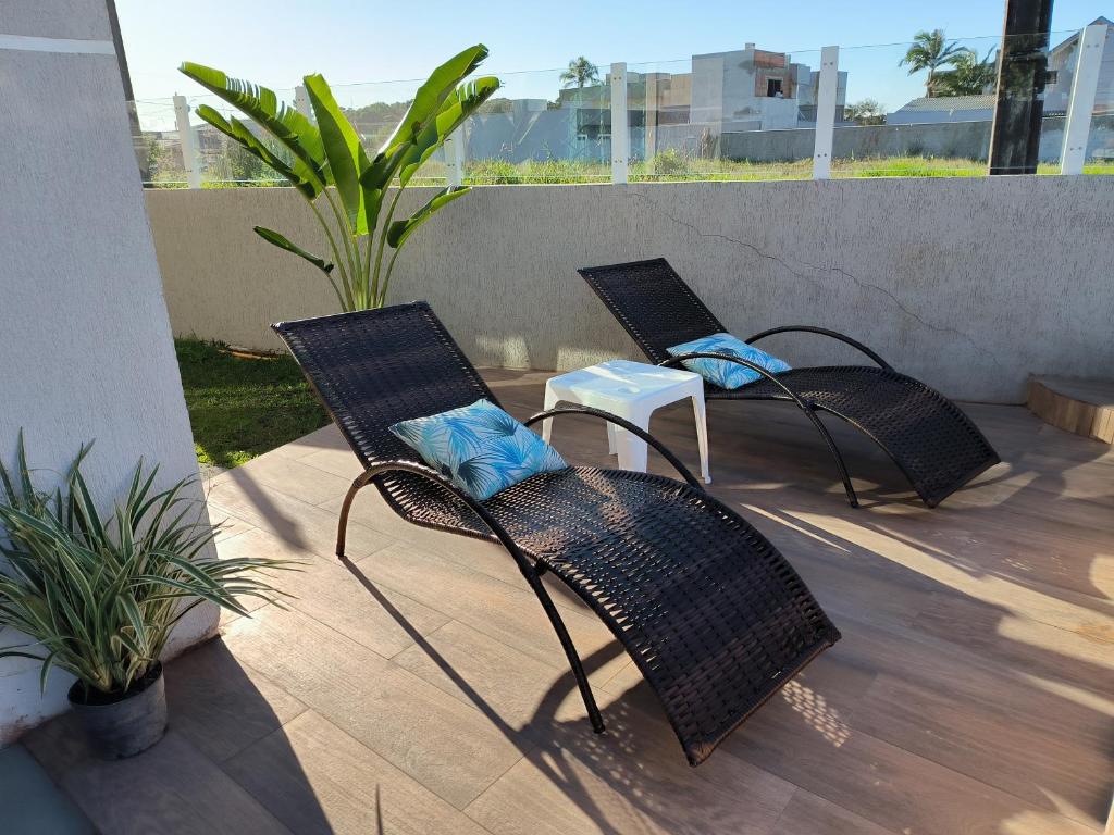 trzy wiklinowe krzesła i stół na patio w obiekcie Casa alguns passos do mar com piscina e SPA Aquecido w mieście Guaratuba