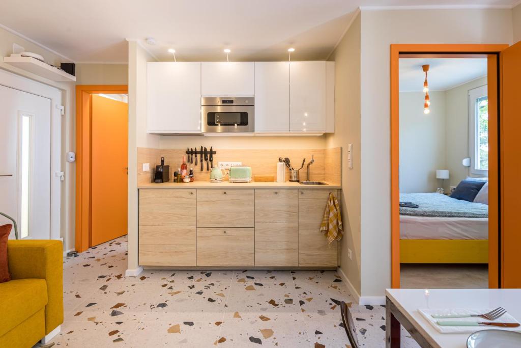 a kitchen with white cabinets and a bed in a room at Balatonic Orange in Zamárdi