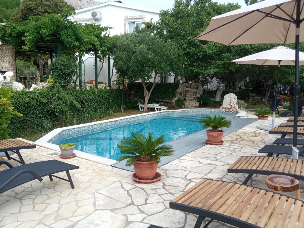 een zwembad met tafels en stoelen en een parasol bij KATY&MLADEN in Baška