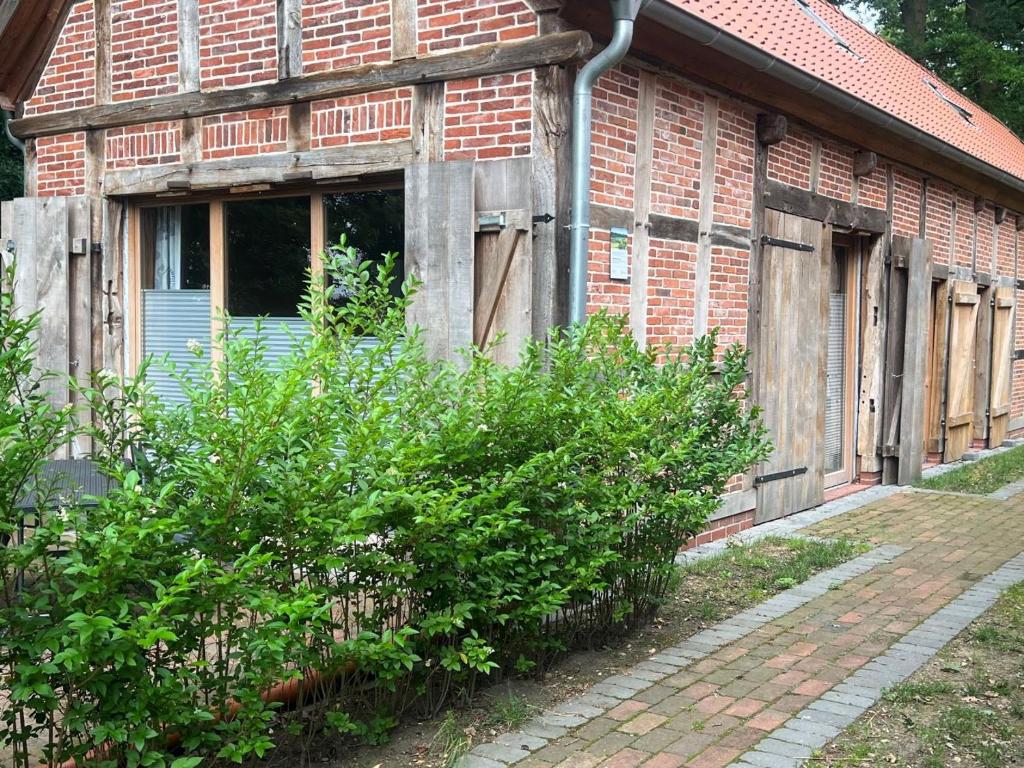 an old brick building with a window and some bushes at Eichenhof Artland in Badbergen