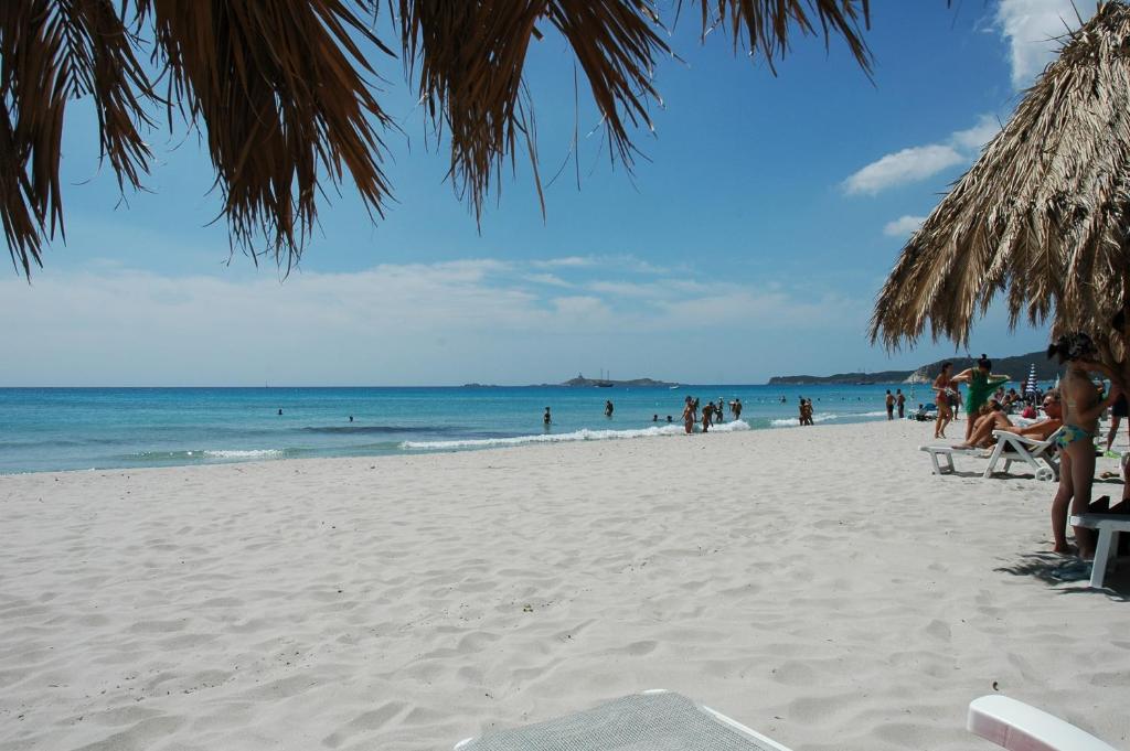 a group of people on a beach with the ocean at Residence Fenicia in Villasimius