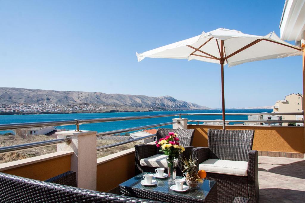 a balcony with a table and chairs and an umbrella at Apartments Belveder in Pag