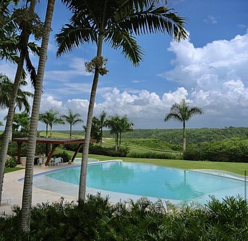 una piscina con palmeras en un complejo en Srvittinivillas Aptla F1 Best Loc and View Lux Altos D Chavon Cdc, en La Romana