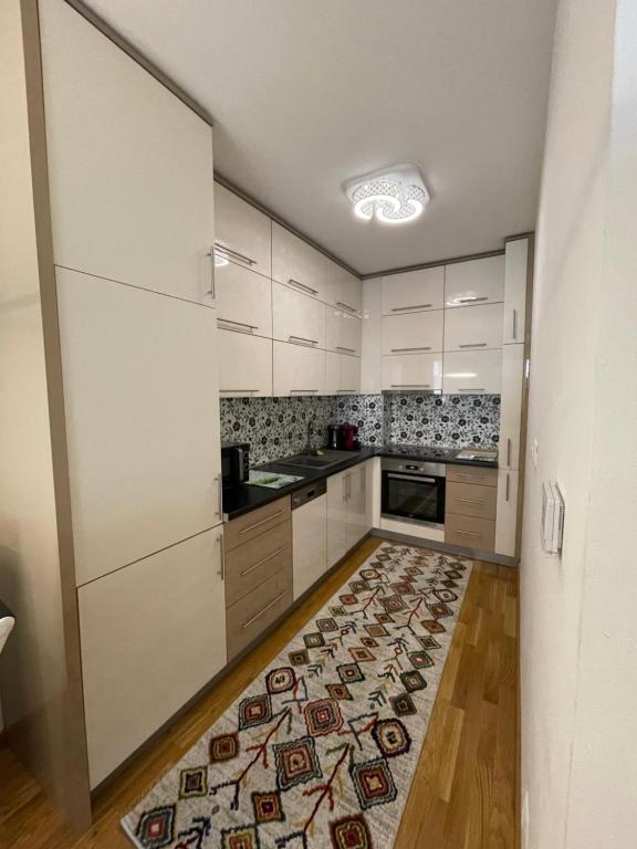 a kitchen with white cabinets and a rug on the floor at Sarajevo Apartment in Sarajevo
