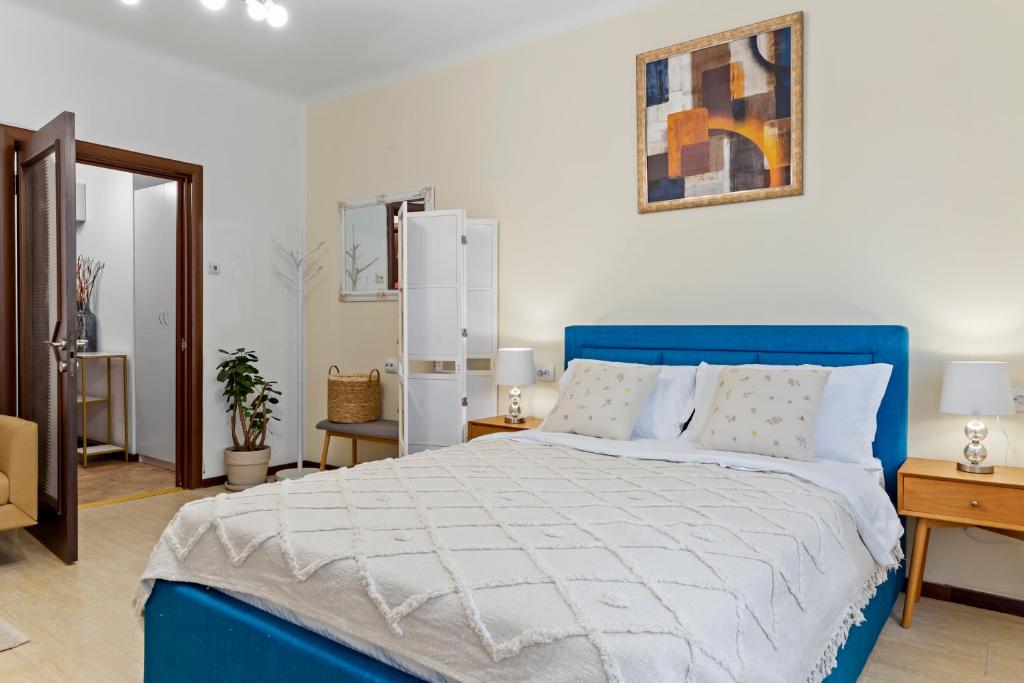 a bedroom with a blue bed and a refrigerator at Upscale Studio, Walking Distance from The Old Town in Bucharest