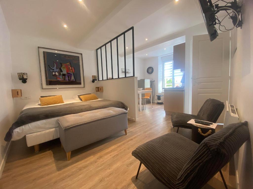 Schlafzimmer mit einem Bett, einem Schreibtisch und Stühlen in der Unterkunft Il y a de l'amour dans l'air - studio lit king size in Arromanches-les-Bains