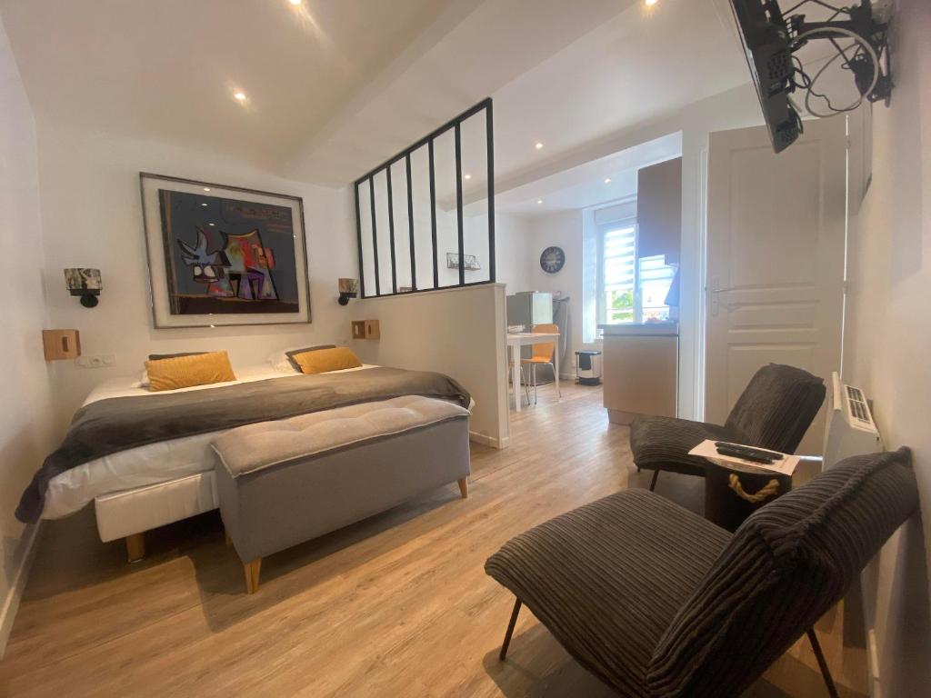 a bedroom with a bed and a desk and chairs at Il y a de l'amour dans l'air - studio lit king size in Arromanches-les-Bains