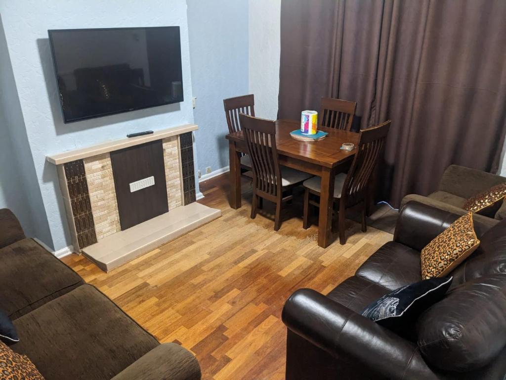 a living room with a couch and a table with a television at Edgefield House in Barking