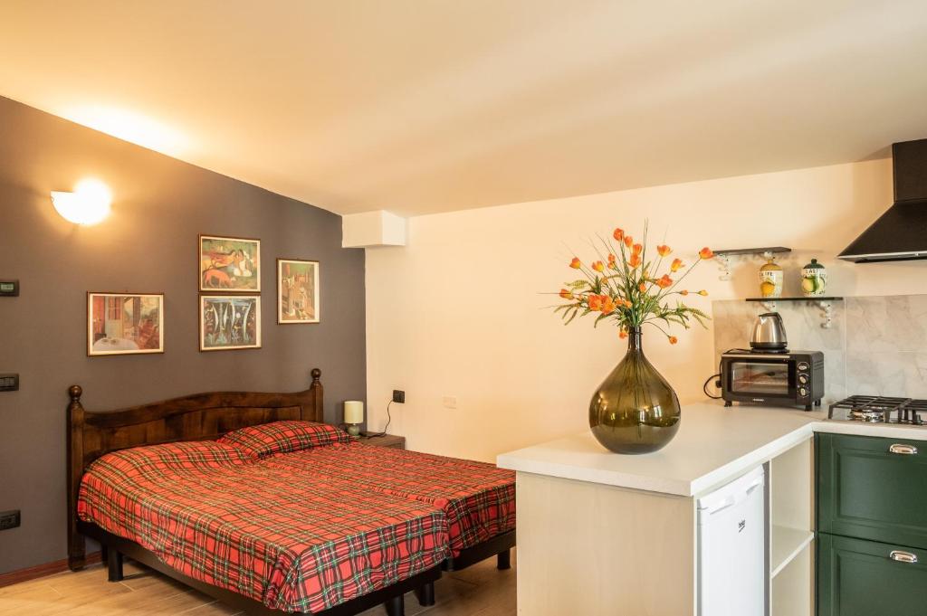 - une chambre avec un lit et un vase de fleurs sur un comptoir dans l'établissement Appartamenti Edolo, à Edolo
