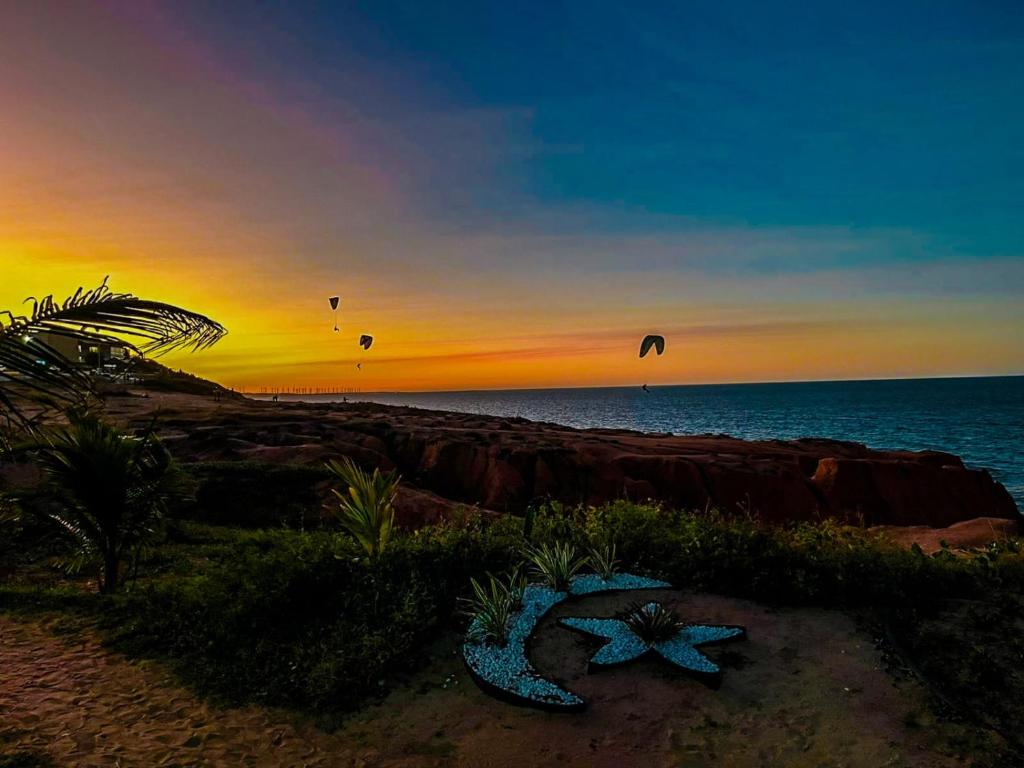 a group of kites flying over the beach at sunset at Raio de Sol Residence in Canoa Quebrada