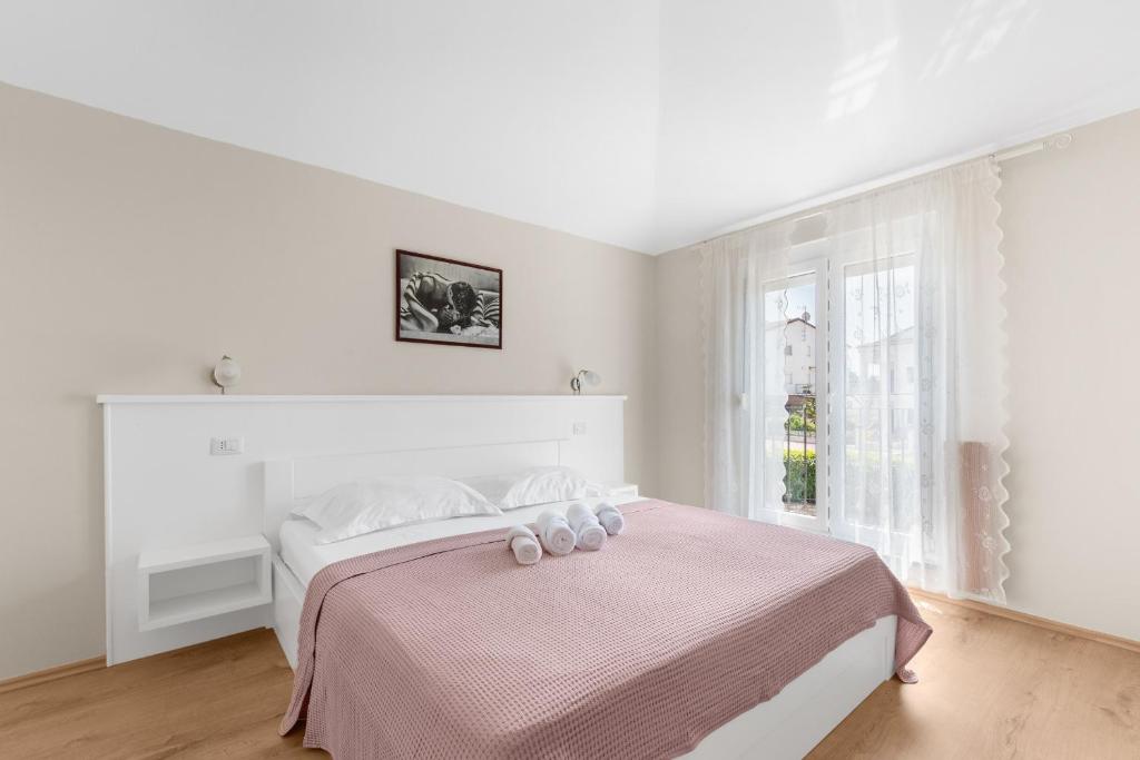 biała sypialnia z łóżkiem z różowym kocem w obiekcie Villa Hope Apartments w Poreču