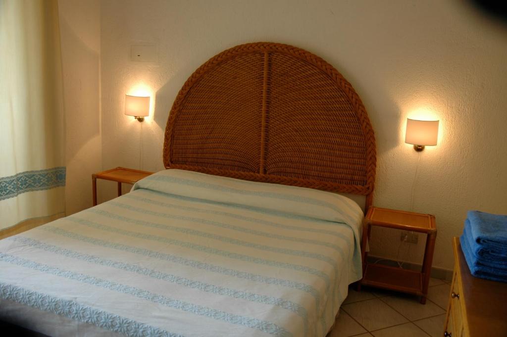 a bedroom with a large bed with a wooden headboard at Residence Fenicia in Villasimius