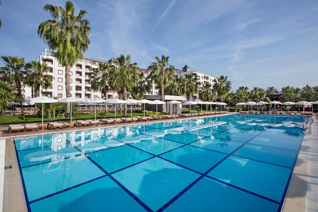 una gran piscina con sillas y sombrillas en Royal Garden Beach Hotel, en Konaklı