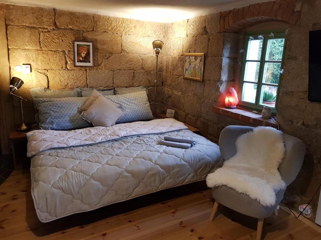 a bedroom with a white bed and a chair at ENJOY Cozy Romance Hills Forest Gardens Views Sauna Whirlpool Bath in Jablonné v Podještědí