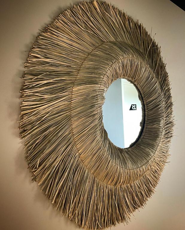 a rattan mirror hanging on a wall at Hôtel Restaurant BO &amp; MIA in La Baule