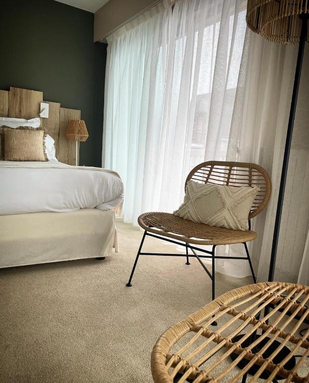 a bedroom with a bed and a chair and a window at Hôtel Restaurant BO &amp; MIA in La Baule