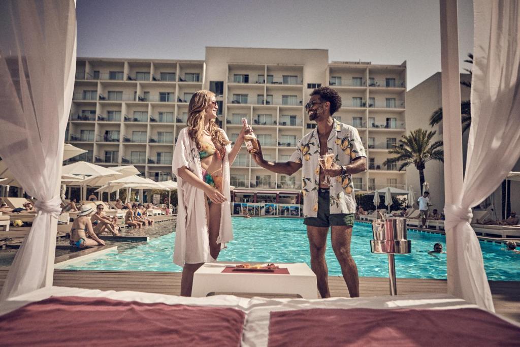 a man and a woman standing in front of a pool at Hotel Astoria Playa Adults Only 4* Sup in Port d'Alcudia