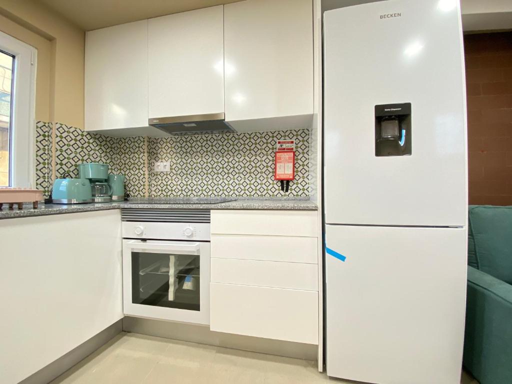 a white kitchen with a refrigerator in a room at Palmela Downtown Terrace in Palmela