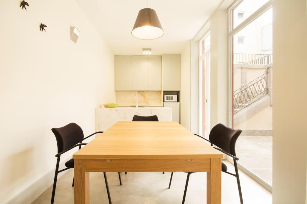uma sala de jantar com uma mesa de madeira e cadeiras pretas em OHH - Santo Ildefonso flat no Porto