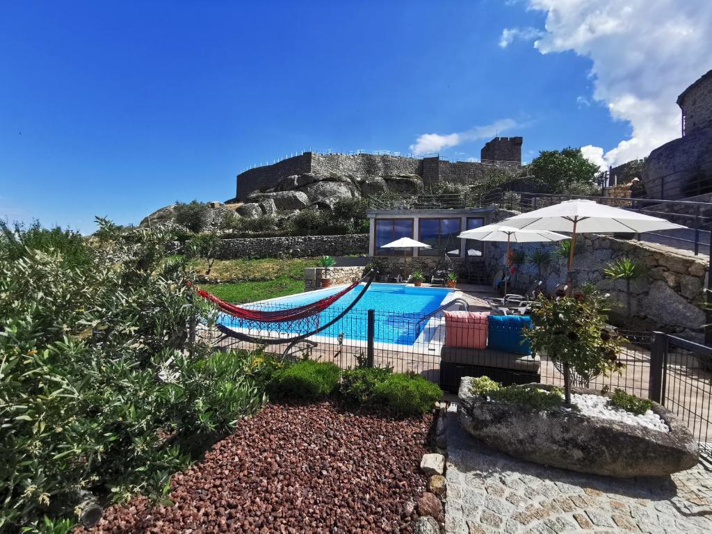 ein Resort mit einem Pool, einer Hängematte und einem Gebäude in der Unterkunft Casa do Penedo Castle House in Linhares