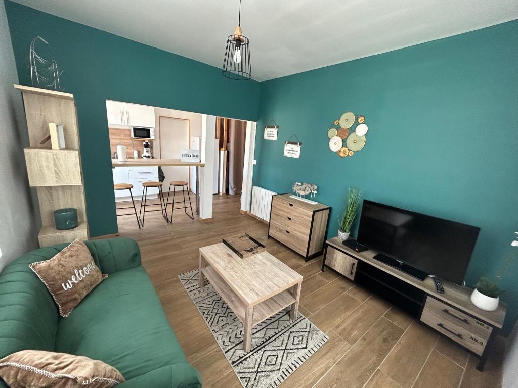 un salon avec un canapé vert et une télévision dans l'établissement Le LH CENTRE VILLE, au Havre