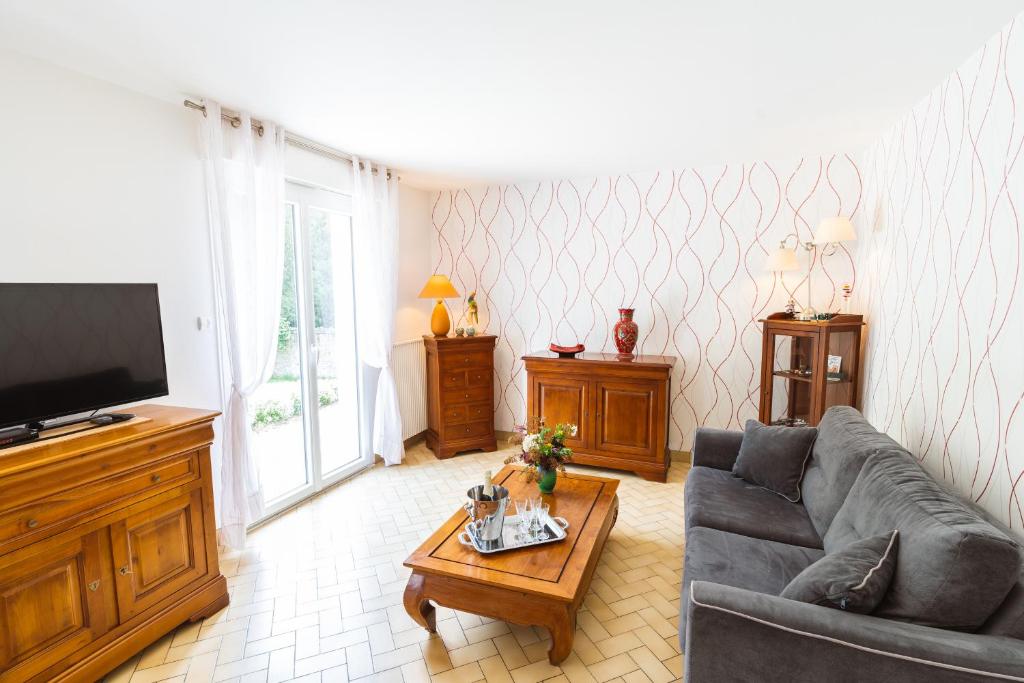 een woonkamer met een bank en een tv bij Clos Fleuri : Amboise Home with Amazing Gardens in Amboise