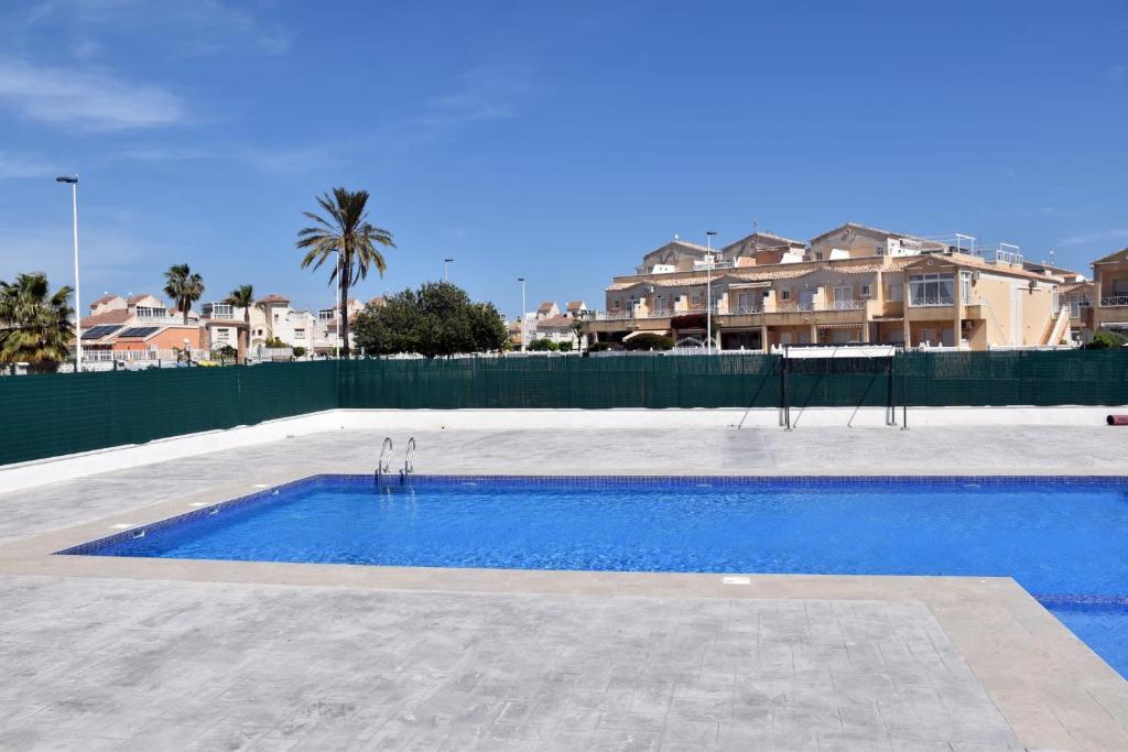 a large swimming pool with blue water in front of houses at Casa Alex Torrevieja- Holiday House - con piscina comunitaria in Torrevieja
