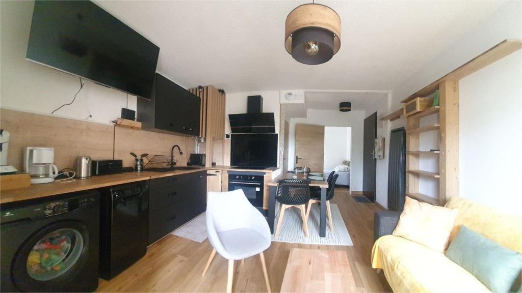 a kitchen with black cabinets and a living room with a couch at Appartement rez de jardin proche du centre ville de sarzeau in Sarzeau