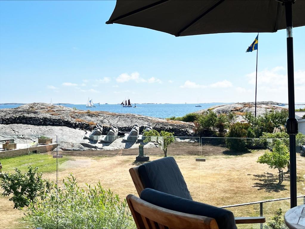 a patio with an umbrella and chairs and the ocean at Unique holiday accommodation on Langholmen in Gothenburgs western archipelago in Torslanda