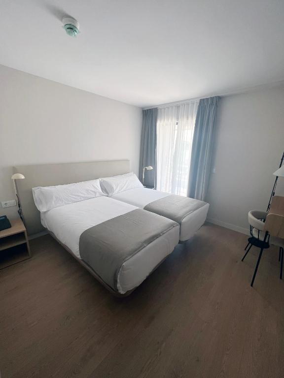 a bedroom with a large white bed and a window at Hotel H4 Cangas 3 Superior in Cangas de Morrazo