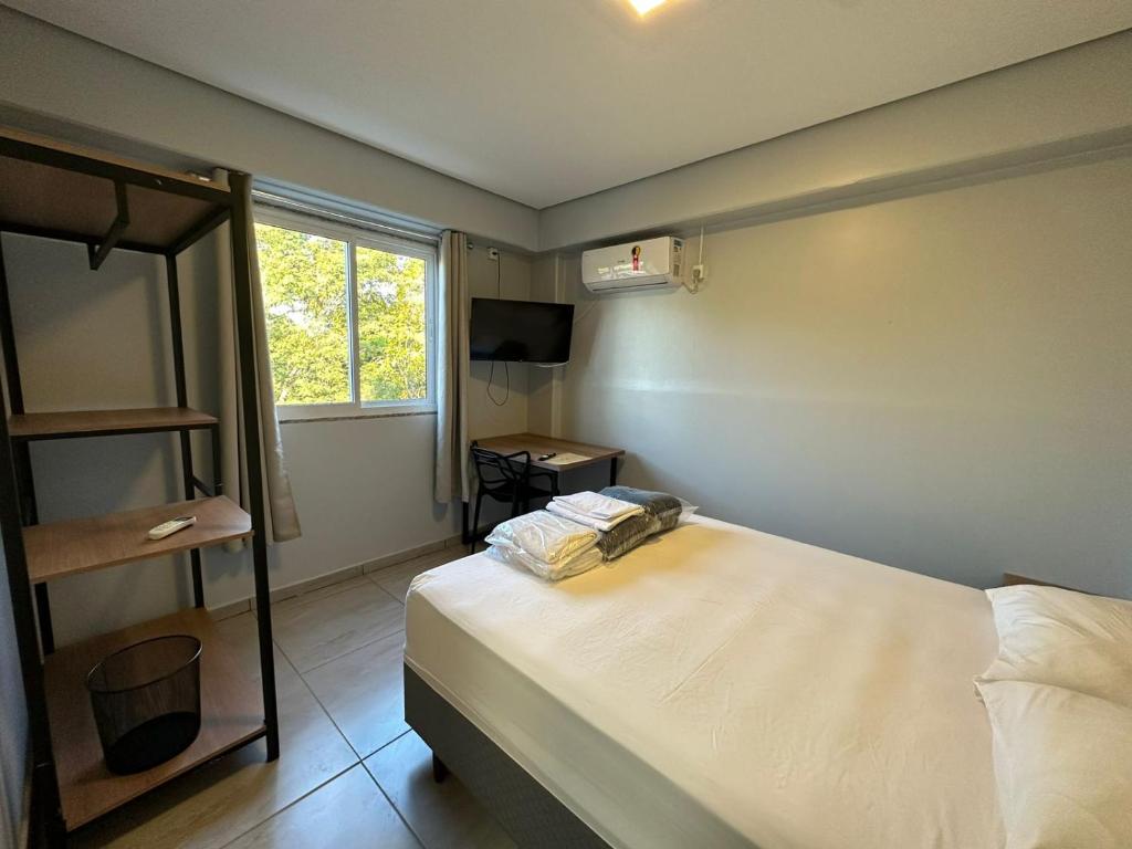 een kleine slaapkamer met een bed en een raam bij WS SUÍTES HOTEL in Três Passos