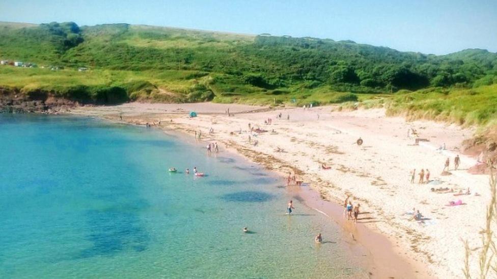 eine Gruppe von Menschen am Strand im Wasser in der Unterkunft Manorbier Castle Inn Bay Room in Manorbier