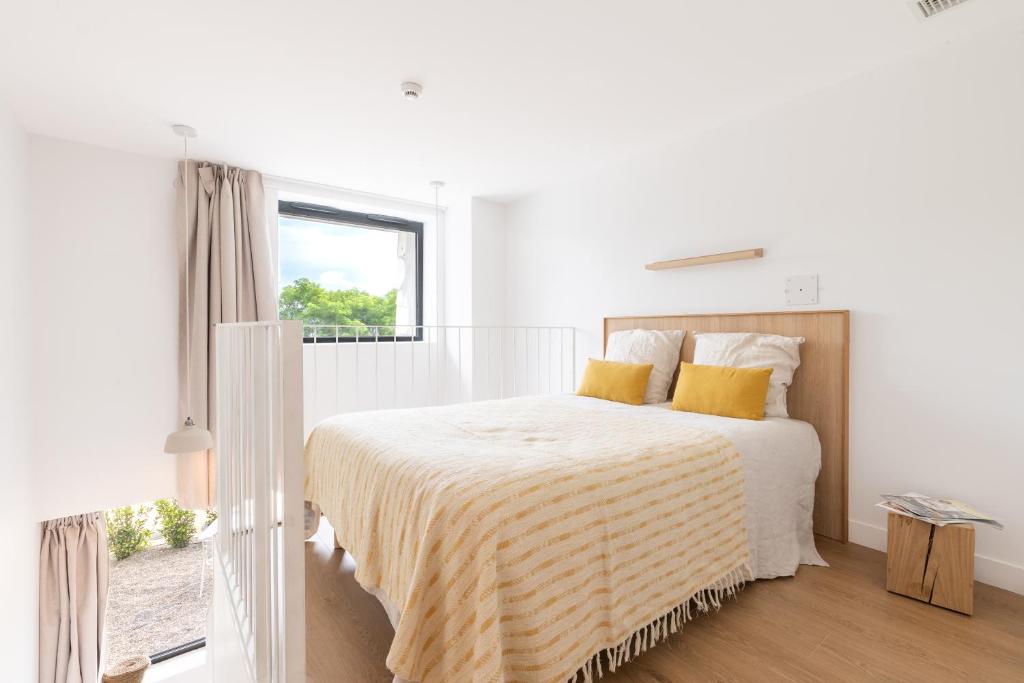 a white bedroom with a large bed with yellow pillows at Les Appartements de Grenoble in Grenoble