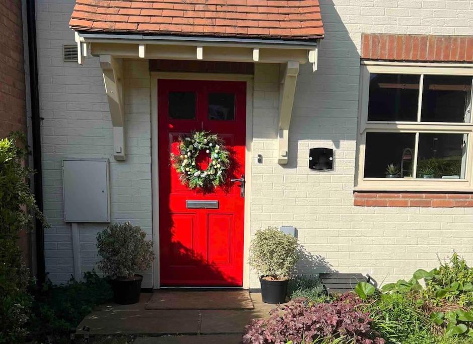 Una puerta roja de una casa con una corona. en NEW! 3 bedroom. On-drive parking. Close to the A1, en Long Bennington