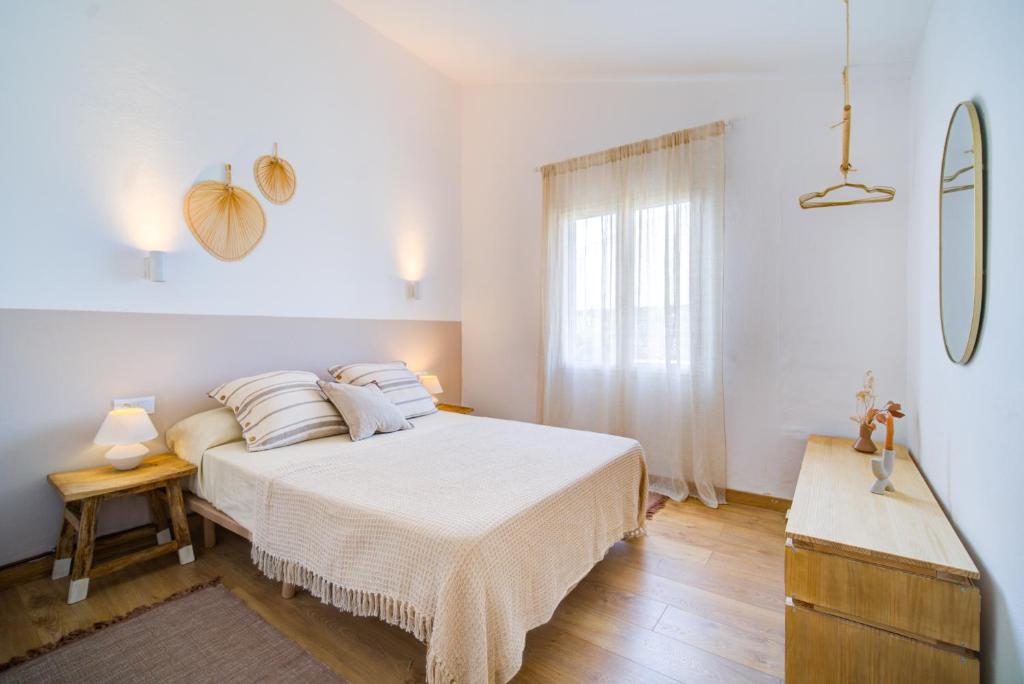 une chambre blanche avec un lit et une fenêtre dans l'établissement Surmar - Apartamento con piscina en Cap d'Artrutx, à Cala'n Bosch
