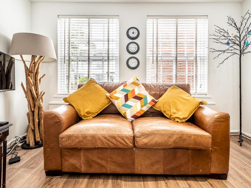 a living room with a brown leather couch with yellow pillows at Pass the Keys Stylish family home central Topsham with parking in Exeter